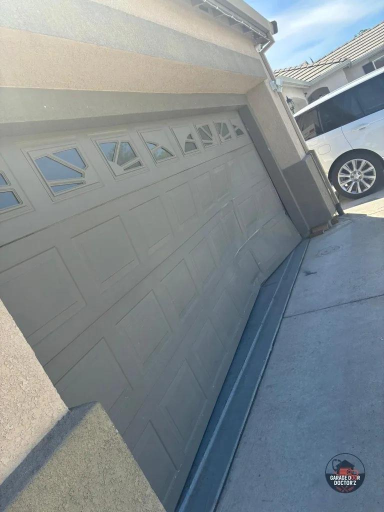 A door off its track, before the repair — the roller has left the vertical track and the panel is carrying load it was never meant to.